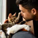 a young man discusses the importance of cat neuter with his small, tabby striped kitten