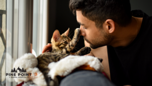 a young man discusses the importance of cat neuter with his small, tabby striped kitten